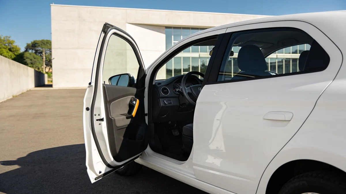 Carro com a porta do motorista aberta, mostrando o comando manual na coluna de direção